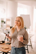 © JustLife - Young woman in office. Beautiful woman on coffee break using phone.