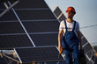 © standret - Cordless screwdriver in hand. Male worker in blue uniform outdoors with solar batteries at sunny day