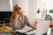© JustLife - Young tired businesswoman in the office. Beautiful woman sitting in office having headache.