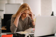 © JustLife - Young tired businesswoman in the office. Beautiful woman sitting in office having headache.