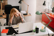 © JustLife - Young tired businesswoman in the office. Beautiful woman sitting in office having headache.