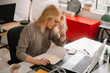 © JustLife - Young tired businesswoman in the office. Beautiful woman sitting in office having headache.