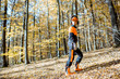 Lifestyle portrait of a professional lumberjack in protective workwear walking with a chainsaw in the forest