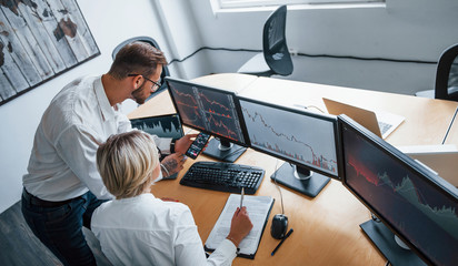 top view. two stockbrokers in formal clothes works in the office with financial market