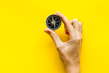 Wall Mural - Choose direction concept. Compass in hand on yellow background top view copy space