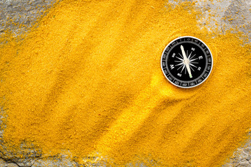 Wall Mural - Travel concept. Compass on yellow sand background top view copy space