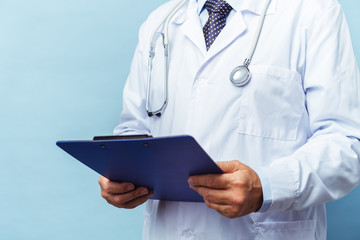 Medical senior doctor with a stethoscope. On a blue background. The medic holds the folder in his hands and makes an appointment at the clinic. Disease prevention concept