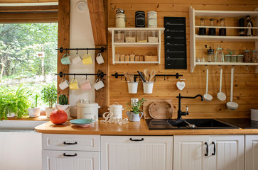 Interior of kitchen in rustic style with vintage kitchen ware and window. White furniture and wooden decor in bright indoor.	