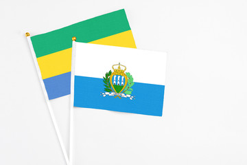 San Marino and Gabon stick flags on white background. High quality fabric, miniature national flag. Peaceful global concept.White floor for copy space.