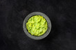 Guacamole in a molcajete, Mexican avocado dip in the traditional stone mortar, shot from the top on a black background