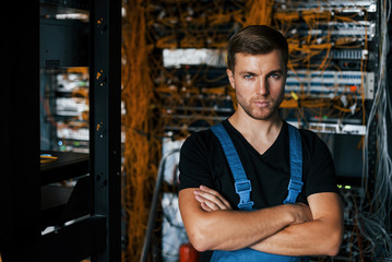 Wall Mural - Young man in uniform stands against internet equipment in server room