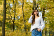 © RomanR - Autumn landscape. Woman in casual wear posing in park with yellow leaves