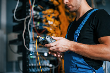 Wall Mural - Young man in uniform have a job with internet equipment and wires in server room