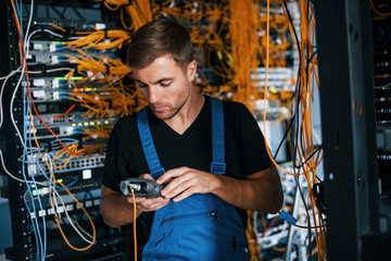Wall Mural - Young man in uniform have a job with internet equipment and wires in server room