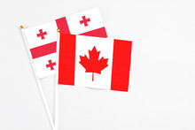 Canada And Georgia Stick Flags On White Background. High Quality Fabric, Miniature National Flag. Peaceful Global Concept.White Floor For Copy Space.