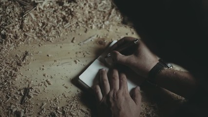 Wall Mural - Carpenter writing notes and measurements in a notebook. Top view.