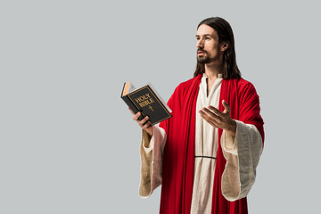 Canvas Print - handsome man gesturing while holding holy bible isolated on grey