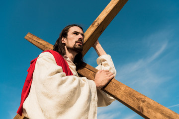 Canvas Print - low angle view of bearded man with wooden cross