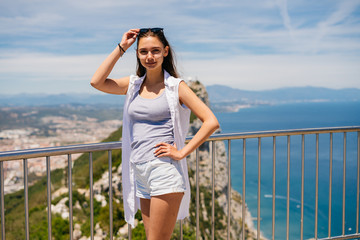 tourist on the bridge, raised sunglasses on her forehead, below the ocean