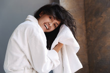 Photo of woman in bathrobe drying her wet hair with towel after shower