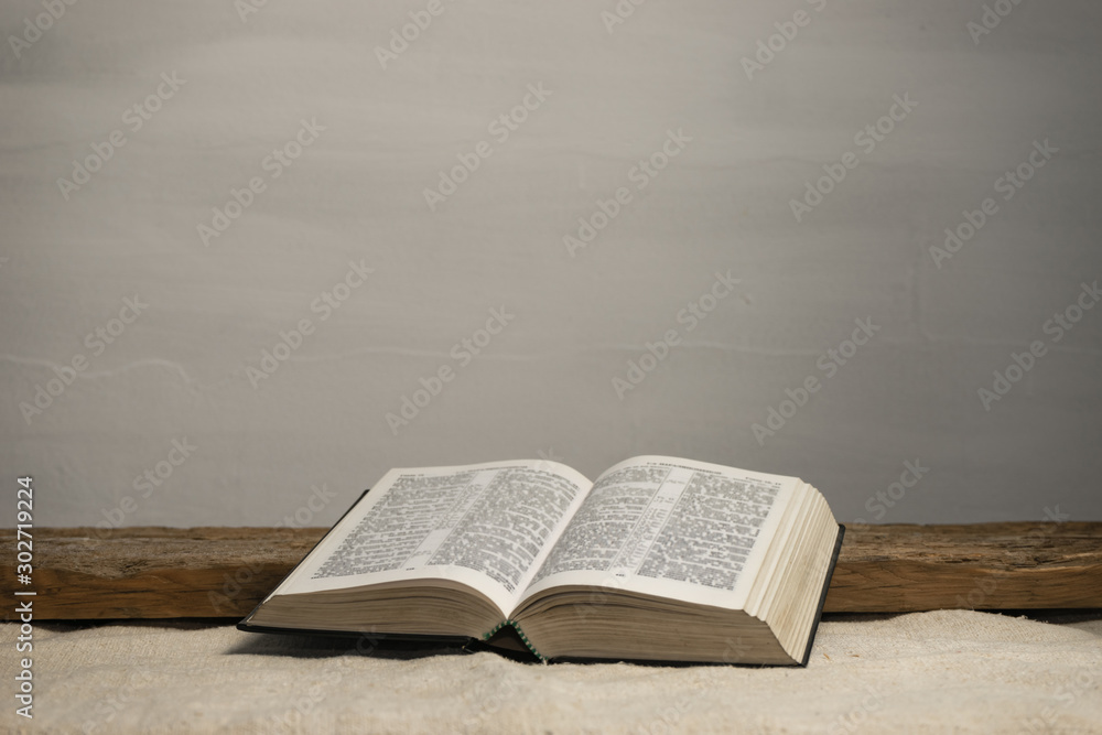 Open Holy Bible on a old wooden table and white wall background. Religion concept. - obrazy, fototapety, plakaty 