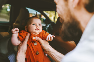 Wall Mural - Father putting infant baby in car family lifestyle dad and child together childhood concept