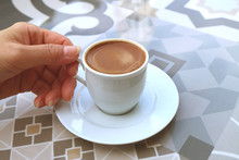 Woman's Hand Holding A Cup Of Turkish Coffee Served On A Moorish Pattern Table