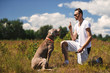 © Alexandr - Man training dog in rural field in summer day