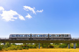 Driverless metro train is moving by overground railroad in countryside area on nature background. Zero emissions of public transport or concept of save environment.