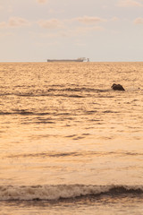 Sunset side view, from the shore, of distant FPSO, Floating Production Storage and Offloading (FPSO) unit, designed to handle 225,000 barrels of oil per day