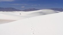 A Single Hiker Climbing A Large White Sand Dune.