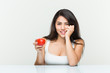 © Asier - Young hispanic woman holding a tomato biting fingernails, nervous and very anxious.