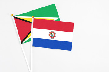 Paraguay and Guyana stick flags on white background. High quality fabric, miniature national flag. Peaceful global concept.White floor for copy space.