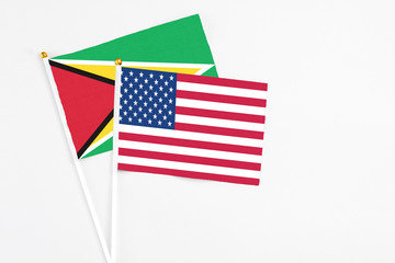 Wall Mural - United States and Guyana stick flags on white background. High quality fabric, miniature national flag. Peaceful global concept.White floor for copy space.