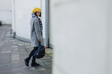 Wall Mural - Attractive young girl in glasses in coat and yellow Beret freestyle walking