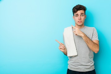 Wall Mural - Young fitness teenager man shocked pointing with index fingers to a copy space.