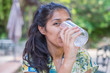 Young indian woman drinking water in the park