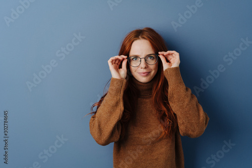 Fotomural Pretty woman with hands raised to her glasses