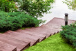 © Александр Беспалый - wooden steps down to the pier on the river, a slope with a landscape of green bushes and a lawn with a lantern.
