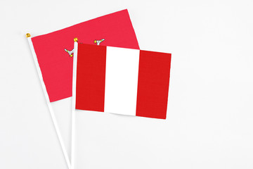 Peru and Isle Of Man stick flags on white background. High quality fabric, miniature national flag. Peaceful global concept.White floor for copy space.