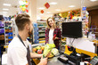 © Pixel-Shot - Male cashier checking out goods in supermarket
