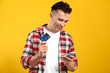 © Pixel-Shot - Young man with credit card and mobile phone on color background