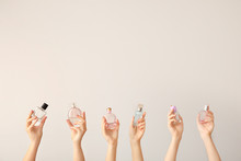 Female Hands With Different Perfume Bottles On Grey Background