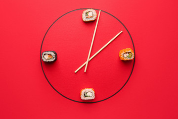 Creative clock made of tasty sushi and chopsticks on color background