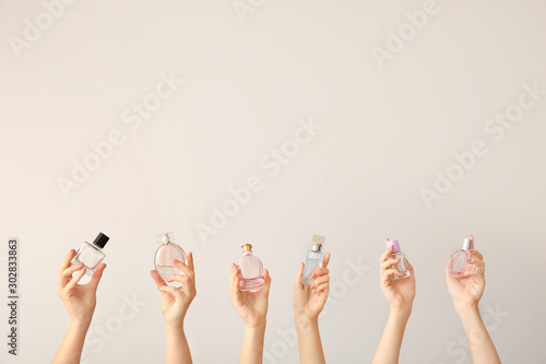 Fotografía Female hands with different perfume bottles on grey background