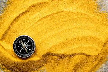 Wall Mural - Travel concept. Compass on yellow sand background top view copy space