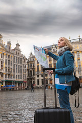 Wall Mural - Woman tourist goes with a suitcase at the Grand Place in Brussels, Belgium