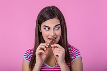 Happy Young Beautiful Lady Eating Chocolate And Smiling. Girl Tasting Sweet Chocolate. Young Woman With Natural Make Up Having Fun And Eating Chocolate Isolated On Pink Background