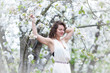 © IrinaN - A portrait of beautiful young Caucasian woman with curly dark hair in blossoming orchard