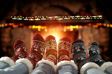 Wall Mural - Blurred background of chrsitmas fireplace.Orange color of warm light of fire.Woman legs with socks and jeans.Copy space.Free place for your decoration.Cold winter december night.Christmas Eve party.